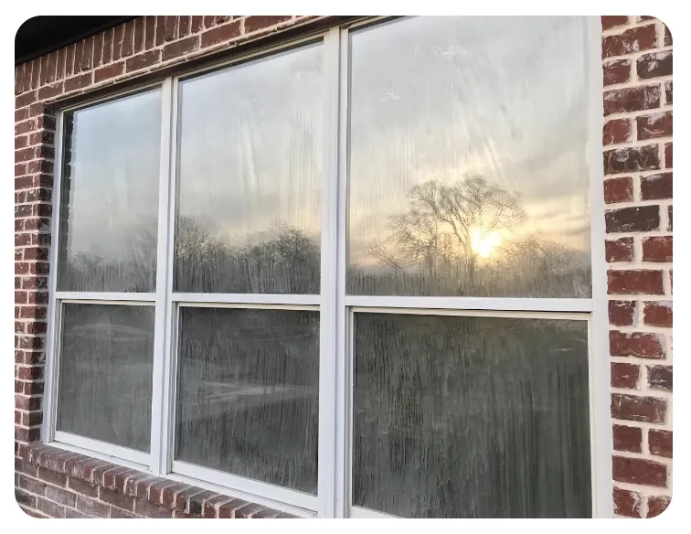 Three-pane window covered in heavy white residue and dirt before cleaning